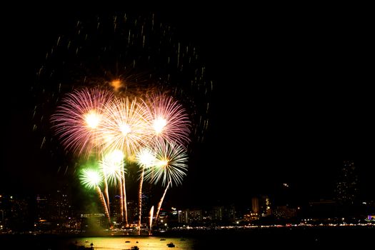 Many flashing fireworks with night cityscape background celebrate New Year.
