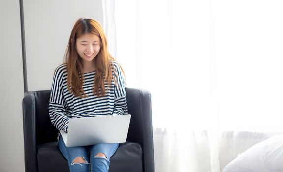 Beautiful of portrait young asian woman using laptop computer  for leisure on chair at living room, girl working online with notebook freelance, communication business concept.