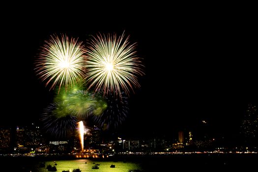 Many flashing fireworks with night cityscape background celebrate New Year.