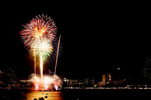 Many flashing fireworks with night cityscape background celebrate New Year.