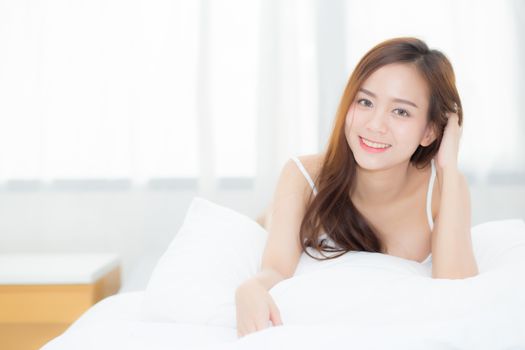 Beautiful portrait young asian woman lying and smile while wake up with sunrise at morning, lifestyle and relax concept.