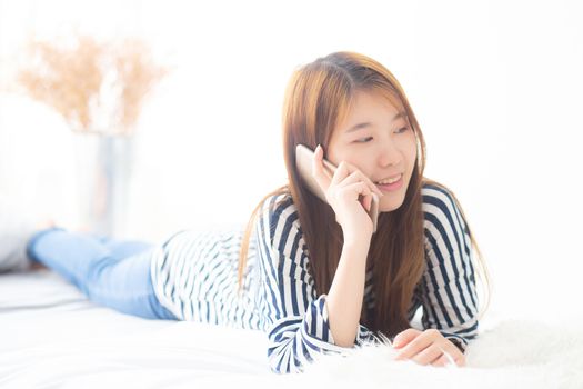 Beautiful young asian woman smiling lying relax on the bed in the morning, girl using mobile smart phone talking enjoy, communication and social network concept.