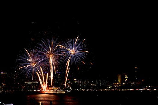 Many flashing fireworks with night cityscape background celebrate New Year.