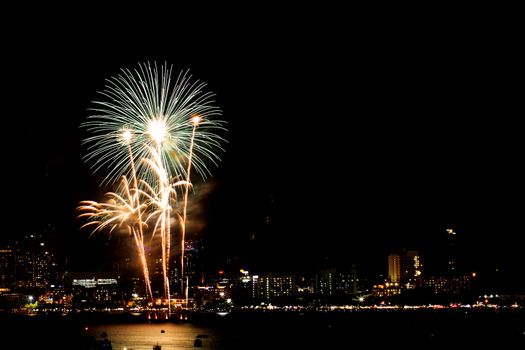 Many flashing fireworks with night cityscape background celebrate New Year.