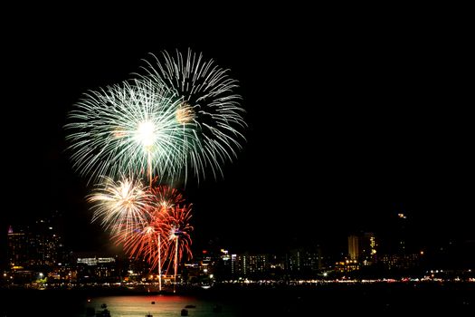 Many flashing fireworks with night cityscape background celebrate New Year.