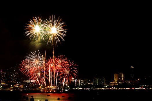 Many flashing fireworks with night cityscape background celebrate New Year.