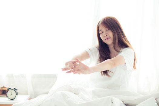 Beautiful of portrait young asian woman stretch and relax in bed after wake up morning at bedroom, new day and resting for wellness, lifestyle concept.