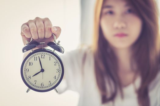 Beautiful asian young woman wake up in morning annoyed alarm clock holding hand, girl hurry wake late with appointment, lifestyle concept.