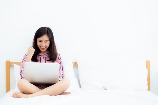 Beautiful of portrait asian young woman sitting relax and leisure with laptop internet online on vacation in bedroom, cheerful of asia girl with gesture glad and success, lifestyle concept.