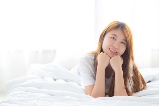 Beautiful portrait young asian woman lying and smile while wake up with sunrise at morning, lifestyle and relax concept.