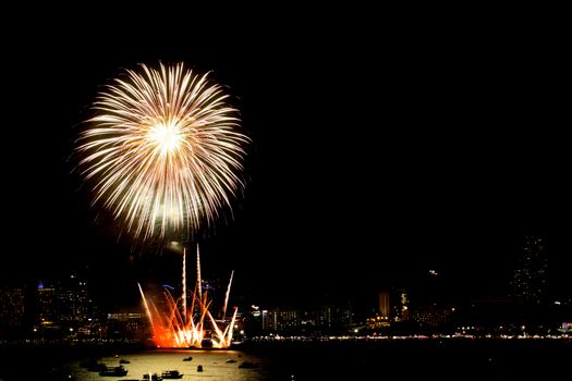 Many flashing fireworks with night cityscape background celebrate New Year.