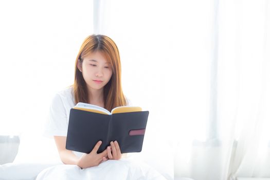 Beautiful of portrait young asian woman relax sitting reading book on bedroom at home, girl study literature, education and llifestyle concept.