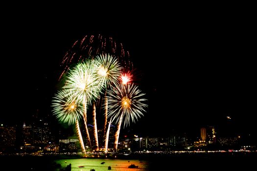 Many flashing fireworks with night cityscape background celebrate New Year.