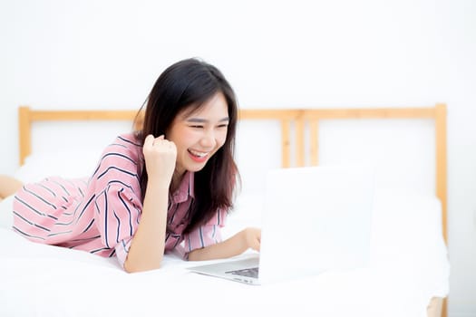 Beautiful of portrait asian young woman lying relax and leisure with laptop internet online on vacation in bedroom, cheerful of asia girl with gesture glad and success, lifestyle concept.