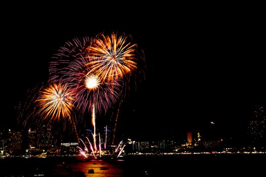 Many flashing fireworks with night cityscape background celebrate New Year.