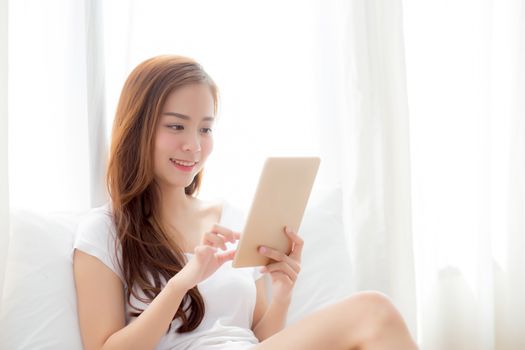 Portrait of beautiful asian young woman with holding and reading digital tablet computer with leisure, girl using tablet with relax at bedroom, lifestyle and communication concept.