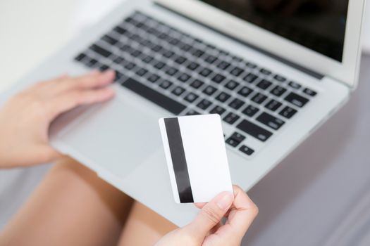 Hand holding credit card using laptop computer shopping online for web e-commerce, girl buying and pay money with debit card, finance and purchase concept.