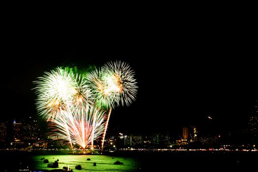 Many flashing fireworks with night cityscape background celebrate New Year.
