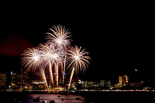 Many flashing fireworks with night cityscape background celebrate New Year.