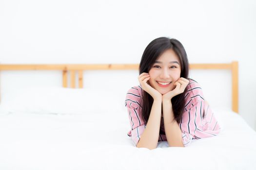 Beautiful portrait young asian woman lying and smile while wake up with sunrise at good morning, girl with happy, lifestyle and relax concept.