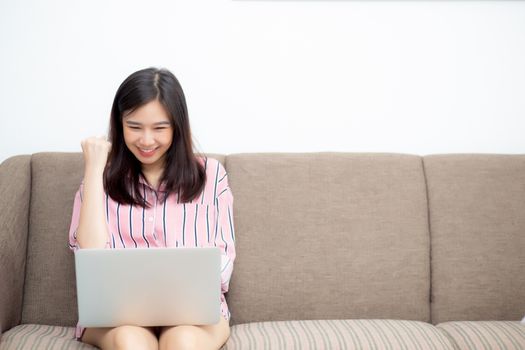 Beautiful of portrait asian young woman excited and glad of success with laptop on sofa, girl working living room at home, career freelance business concept.