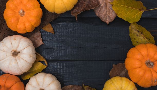 Fall Thanksgiving and Halloween pumpkins and dry leaves on wooden background, top view shot