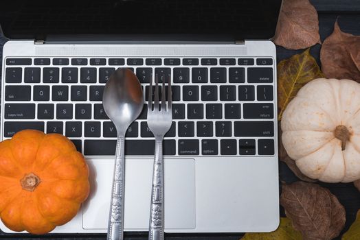 Fall Thanksgiving and Halloween pumpkins, dry leaves and have laptop computer on wooden background, top view shot