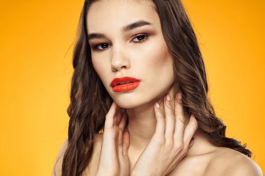 beautiful brunette red lips bare shoulders skin care yellow background. High quality photo