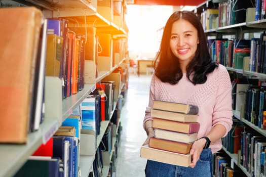 Young woman carrying heavy books in library