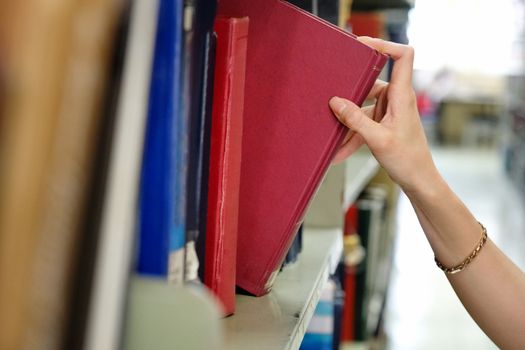 Young woman picking a book off the shelf in a library