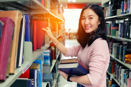 Young woman picking a book off the shelf in a library