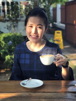 Young woman drinking coffee in in sunshine light enjoying her morning coffee.