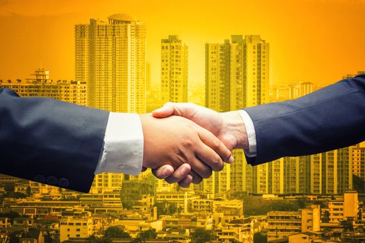Business men shaking hands on cityscape business background