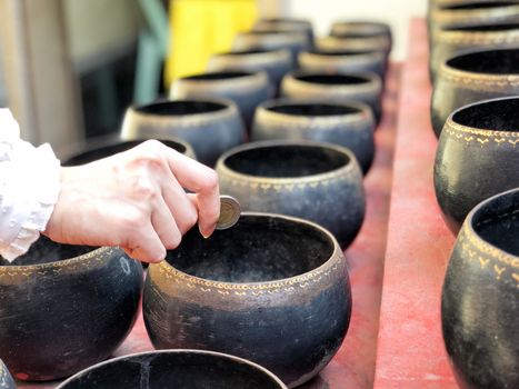 Woman donating money into Buddhist monk's alms bowl for making merit