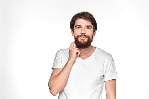 Bearded man in white t-shirt gesture with hands emotions light background. High quality photo