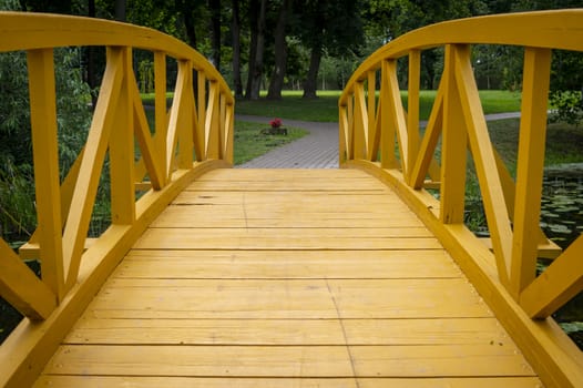 Empty arched wooden pedestrian bridge curving away in a receding perspective outdoors in a park