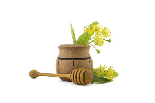 Small wooden pot of freshly picked yellow linden flowers and leaves, also called tilia and wooden wand over a white background