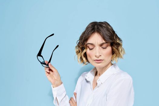 Business woman on a blue background glasses with dark rims curly hair Light shirt cropped view. High quality photo