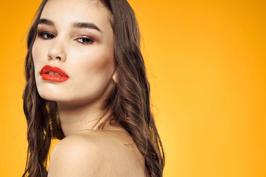beautiful brunette red lips bare shoulders skin care yellow background. High quality photo