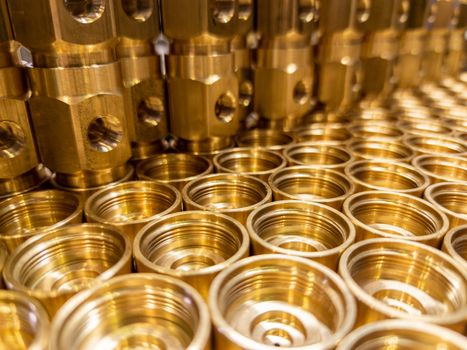 Shiny yellow metal parts background. An abstract industrial close-up background of shiny brass metal threaded hexagonal parts after turning and machining.