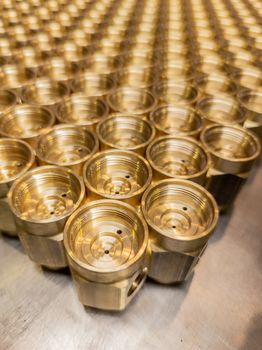 Shiny yellow metal parts background. An abstract industrial close-up background of shiny brass metal threaded hexagonal parts after turning and machining.