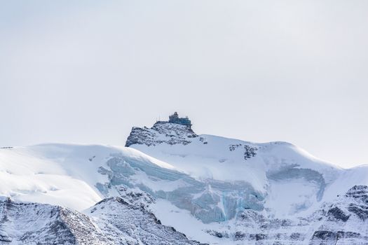 Stunning view of famous Sphinx Observatory, and Jungfraujoch railway station located on Bernese Oberland between Jungfrau and Monch, with glacier and snow on cloudy autumn day, Canton of Bern, Switzerland