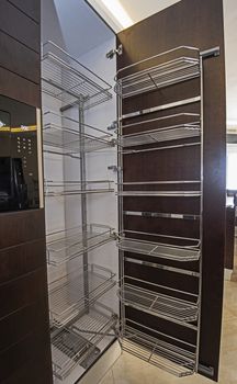 Interior design decor of kitchen in luxury apartment showing closeup detail of large pantry cupboard with shelves
