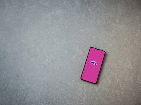 Lod, Israel - July 8, 2020: OkCupid app launch screen with logo on the display of a black mobile smartphone on ceramic stone background. Top view flat lay with copy space.