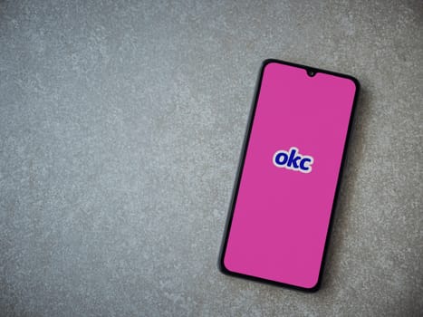 Lod, Israel - July 8, 2020: OkCupid app launch screen with logo on the display of a black mobile smartphone on ceramic stone background. Top view flat lay with copy space.