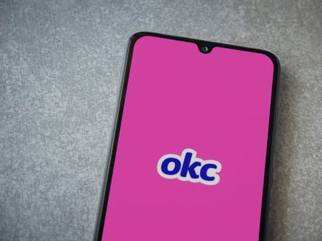 Lod, Israel - July 8, 2020: OkCupid app launch screen with logo on the display of a black mobile smartphone on ceramic stone background. Top view flat lay with copy space.