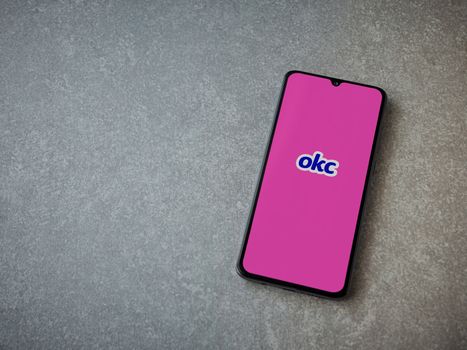 Lod, Israel - July 8, 2020: OkCupid app launch screen with logo on the display of a black mobile smartphone on ceramic stone background. Top view flat lay with copy space.