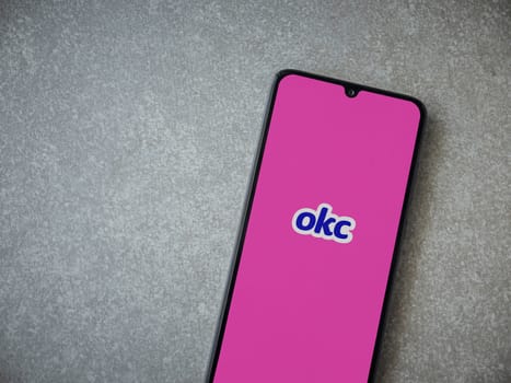 Lod, Israel - July 8, 2020: OkCupid app launch screen with logo on the display of a black mobile smartphone on ceramic stone background. Top view flat lay with copy space.