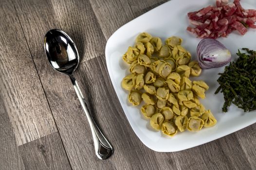 ingredients for cappelletti pancetta and asparagus creamed in a pan with parmesan