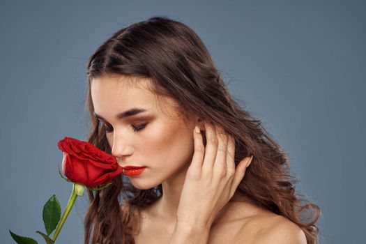 woman with a rose in her hands naked shoulders evening makeup red lips. High quality photo